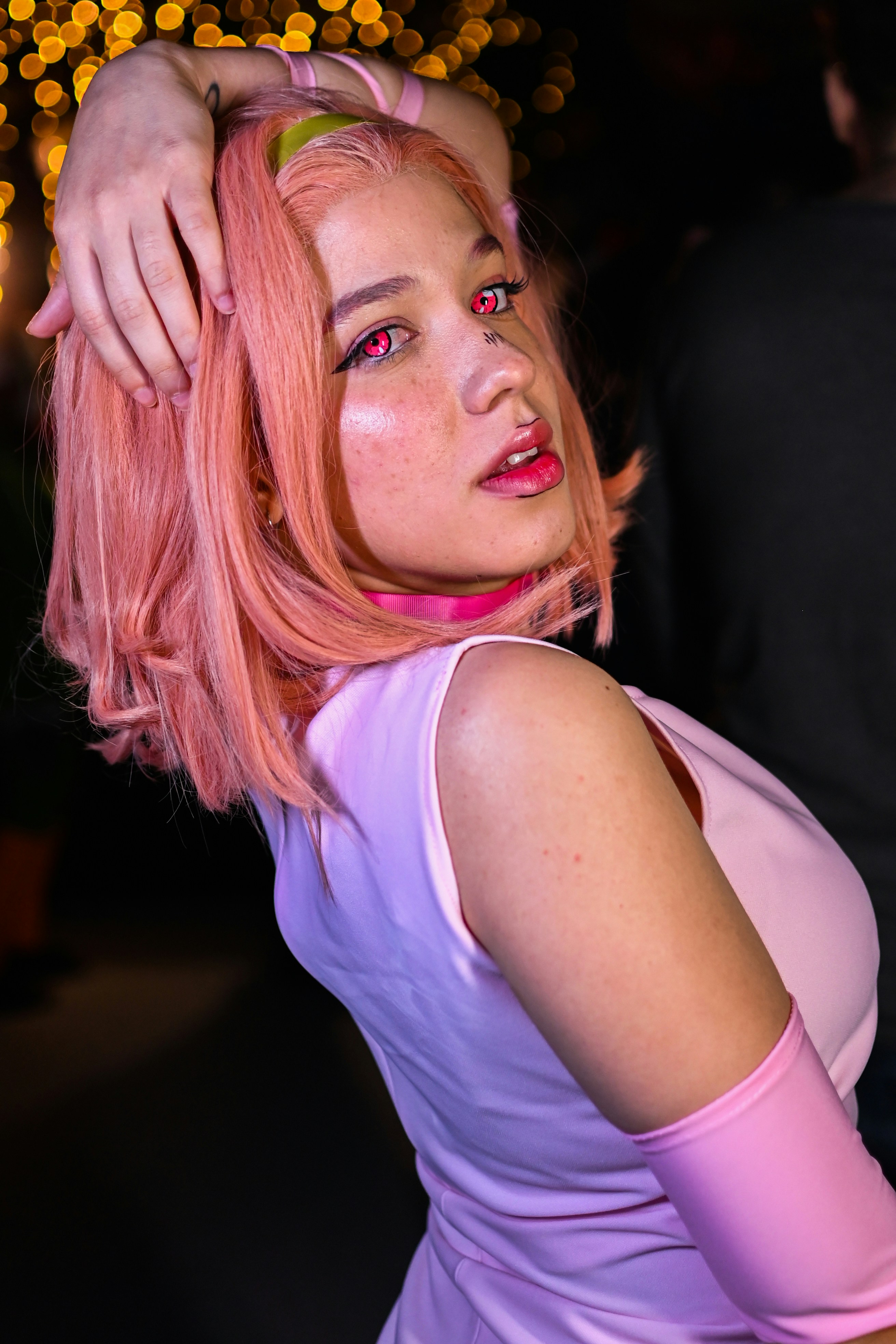 Seorang wanita dengan rambut merah muda sedang berpose untuk berfoto