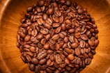 Close-up of freshly roasted Colombian coffee beans in a rustic wooden bowl