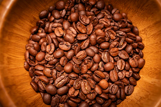 Close-up of expertly roasted coffee beans in a rustic wooden scoop highlighting their rich color.