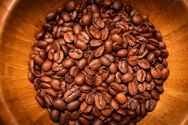 Close-up of freshly roasted coffee beans in a wooden scoop.