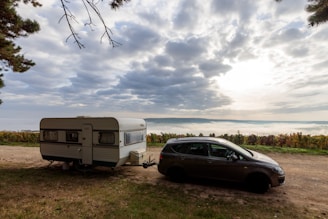 a car parked next to a camper on a dirt road