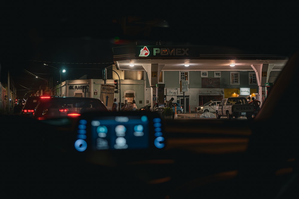 um posto de gasolina à noite com carros estacionados em frente