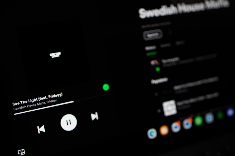 A dark-themed Spotify interface displaying the song 'See The Light' by Swedish House Mafia featuring Fridayy. The play controls are visible with options to play, pause, and skip tracks. The track list and album details are slightly blurred in the background.