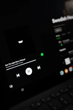 Dark blue and black themed music player interface with red accents showing album art and play controls