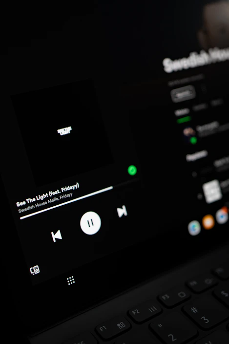Dark blue and black themed music player interface with red accents showing album art and play controls