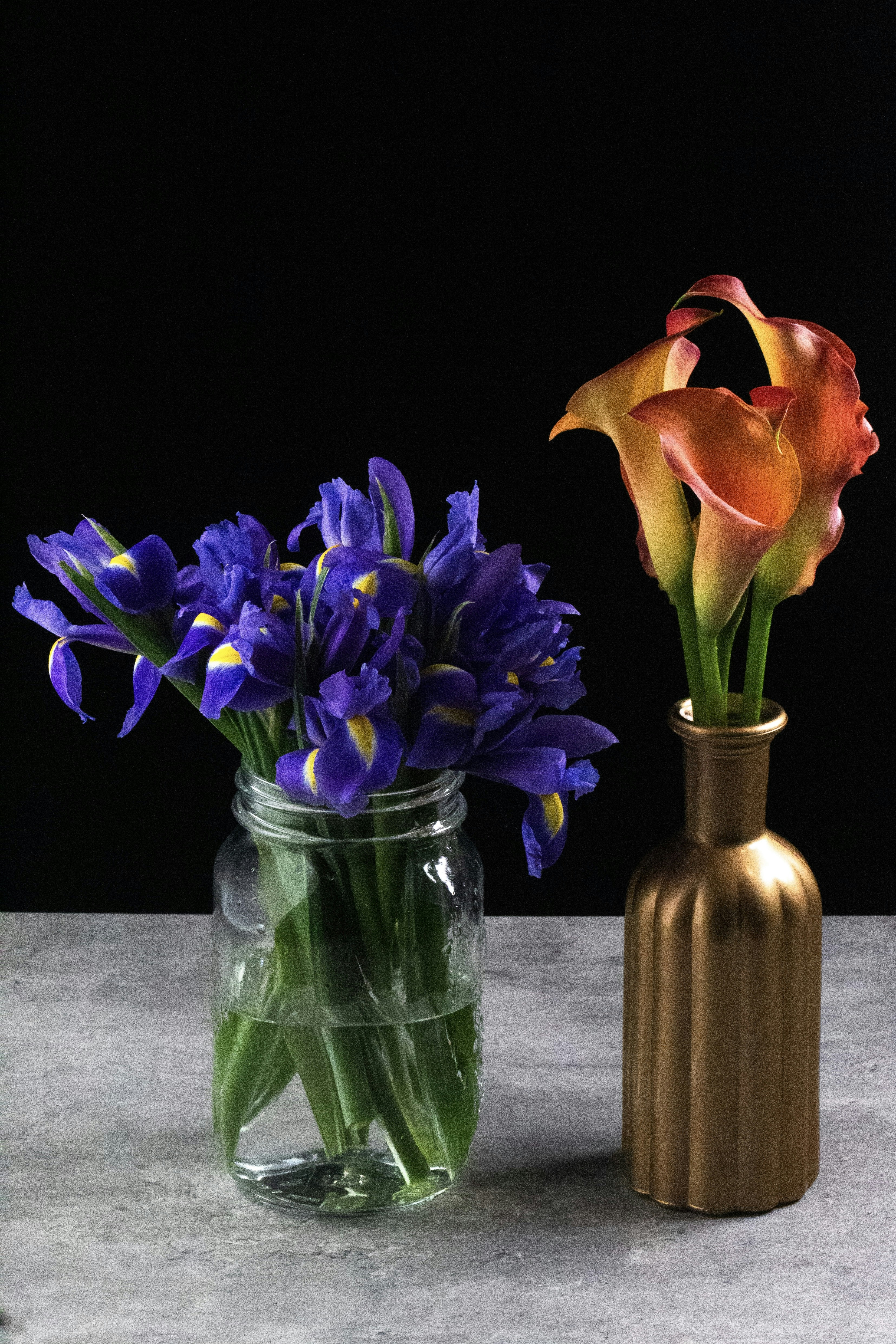 two vases with flowers in them sitting on a table