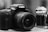 A close-up view of two cameras, one prominently in the foreground and one partially visible in the background. The foreground camera has a large lens and notable branding on top.