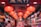 A vibrant shop interior illuminated by a series of red lanterns hanging from the ceiling. The shop is filled with a variety of colorful items and decorations, arranged neatly on shelves. Two people are present, one appearing to browse the merchandise.
