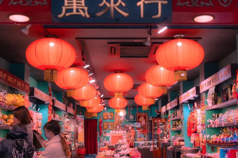 a woman standing in front of a store filled with red lanterns