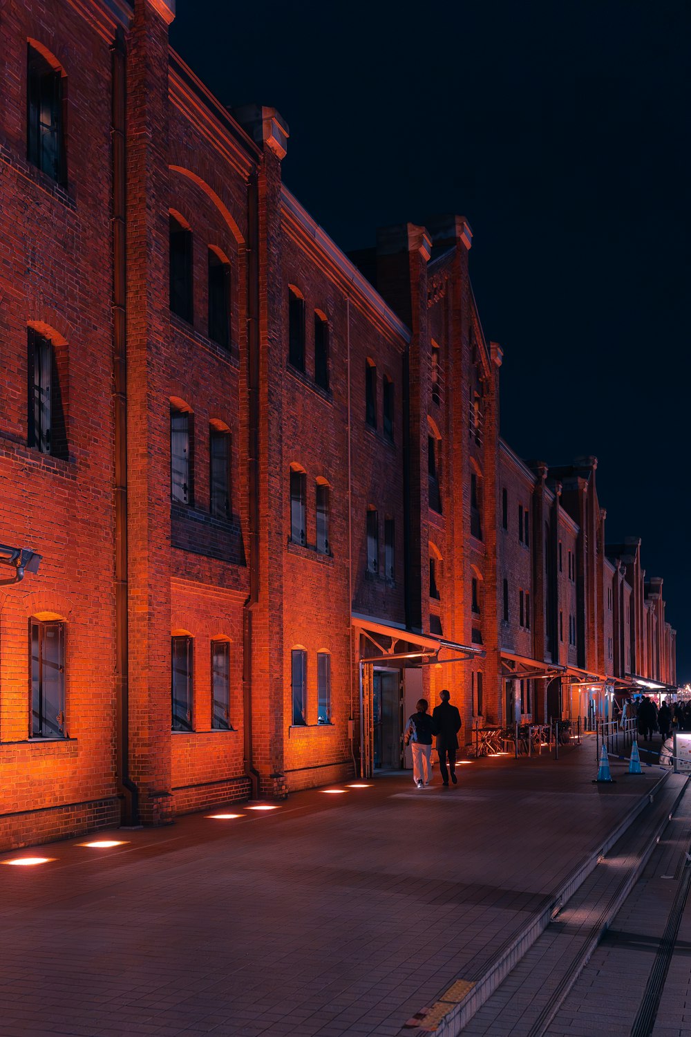 a couple of people walking down a street at night