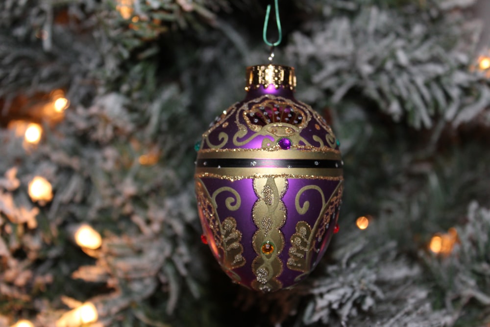 a purple and gold ornament hanging from a christmas tree