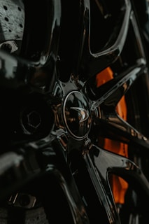 Close-up of a shiny clutch disc resting on a sleek black surface with soft orange lighting highlighting its details.