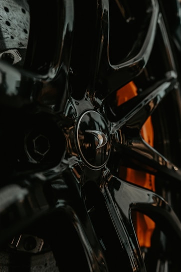 Close-up of a shiny clutch disc resting on a sleek black surface with soft orange lighting highlighting its details.