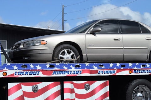 a flatbed tow truck with a silver car on it