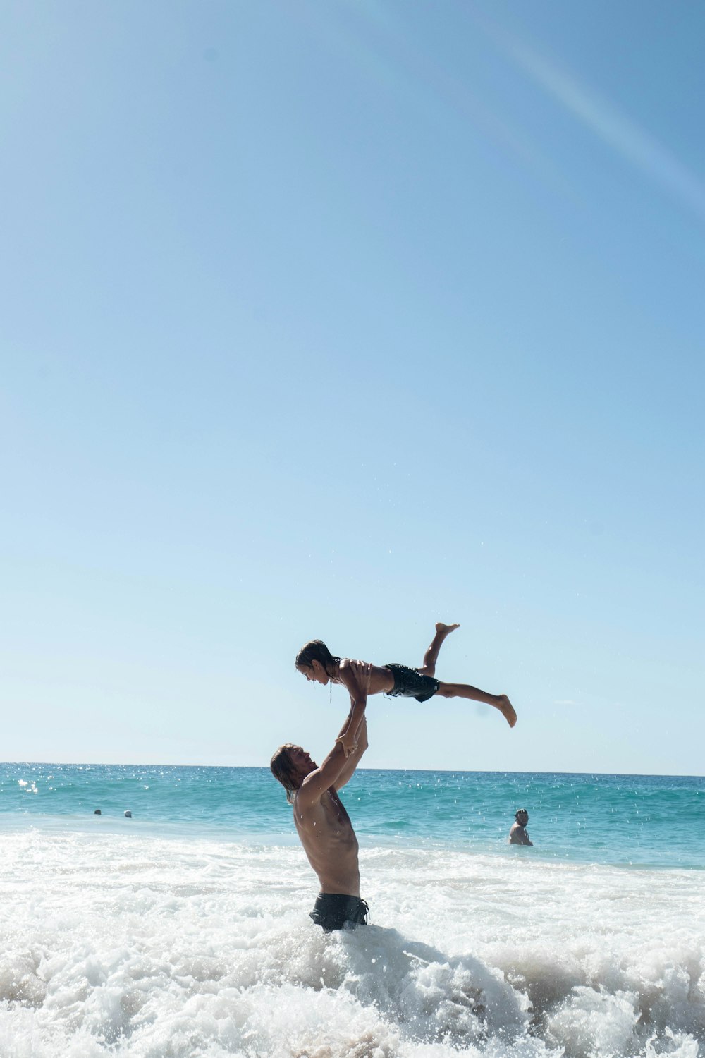 a man holding a young boy on his shoulders in the ocean