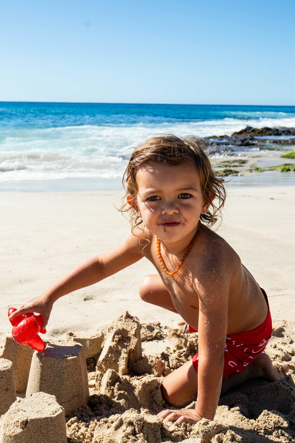 uma menina brincando na areia na praia