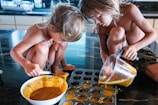 Children mixing ingredients in a large bowl on a kitchen counter.