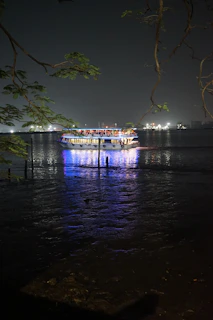 Nighttime shot of a boat lit up with soft lights, floating peacefully on the water.