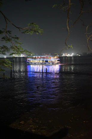 Nighttime shot of a boat lit up with soft lights, floating peacefully on the water.