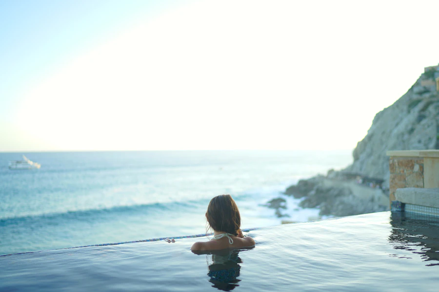 Woman relaxing in an infinity pool overlooking the ocean