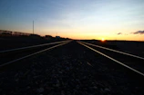 A scenic view of railroad tracks stretching into the horizon under a wide open sky.