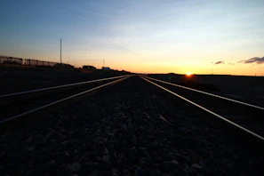 A scenic view of railroad tracks stretching into the horizon under a wide open sky.