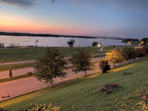 Sunset over the lush green riverside trails filled with families enjoying a peaceful walk