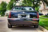 A black luxury sedan parked on a suburban street, featuring an Illinois license plate. The car has dual exhausts and the badge 'ESC' on the back. The background includes green trees and houses with well-manicured lawns.