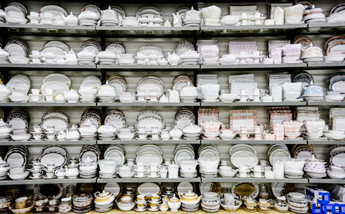 An array of fine china dishes with delicate patterns displayed in a showroom.