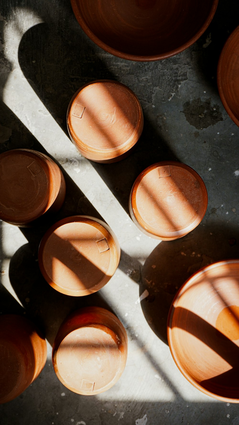 a group of brown bowls sitting on top of a cement floor