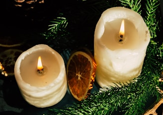 A cozy scene showing natural candles glowing softly beside sprigs of lavender and orange peel.