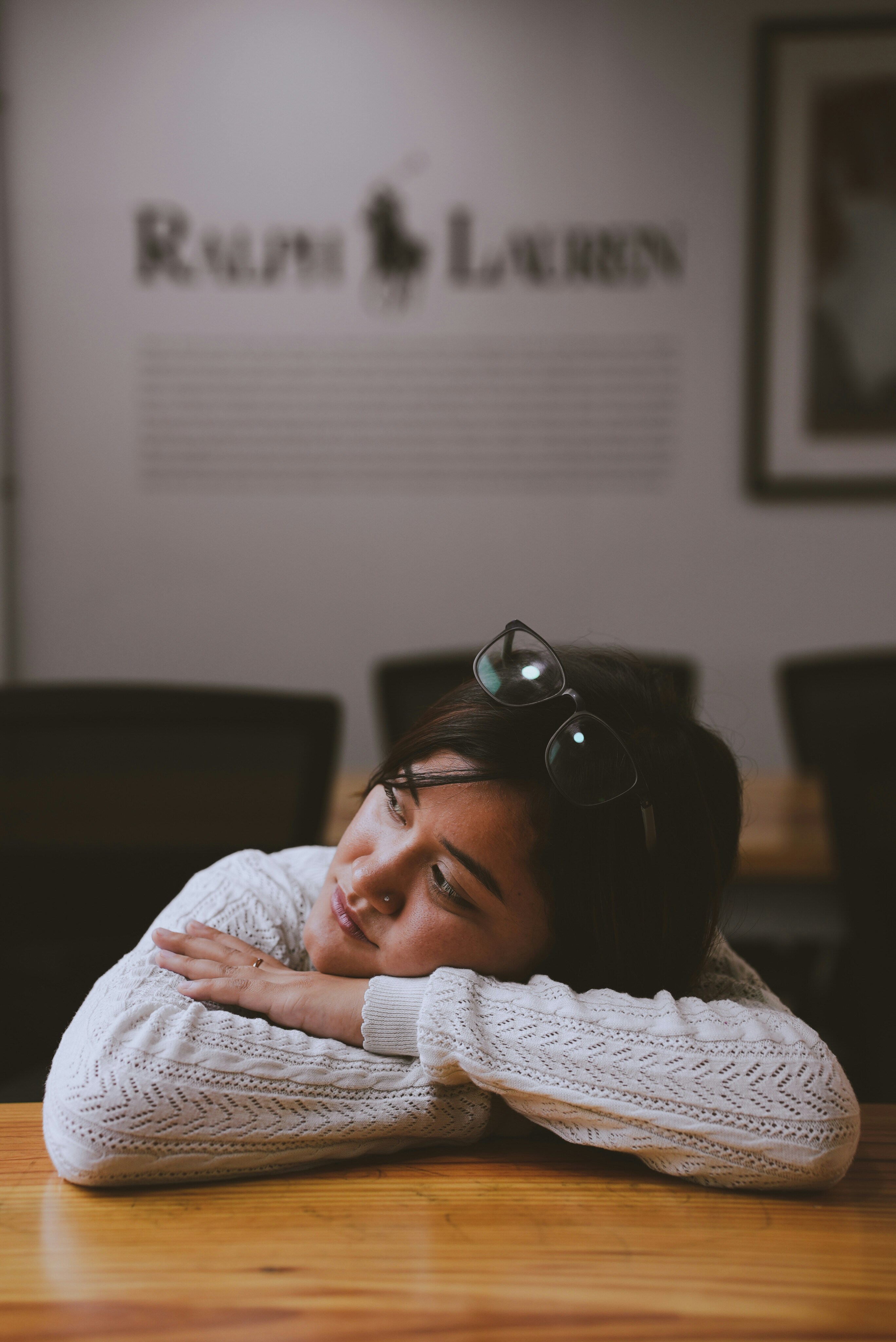A woman sitting quietly at a table with her head resting on her hands, a moment of feeling overwhelmed and unheard