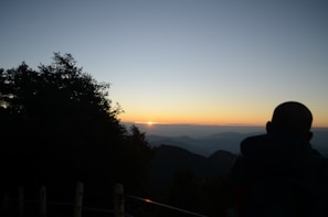 Sunset view from Mont Passot with silhouetted traveler admiring the deep orange sky