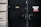 A dark wooden door with multiple signs attached to it, including one indicating a sauna and others related to fire safety and a sprinkler system. The door has visible locks and number pads. It is part of a building with textured beige walls.