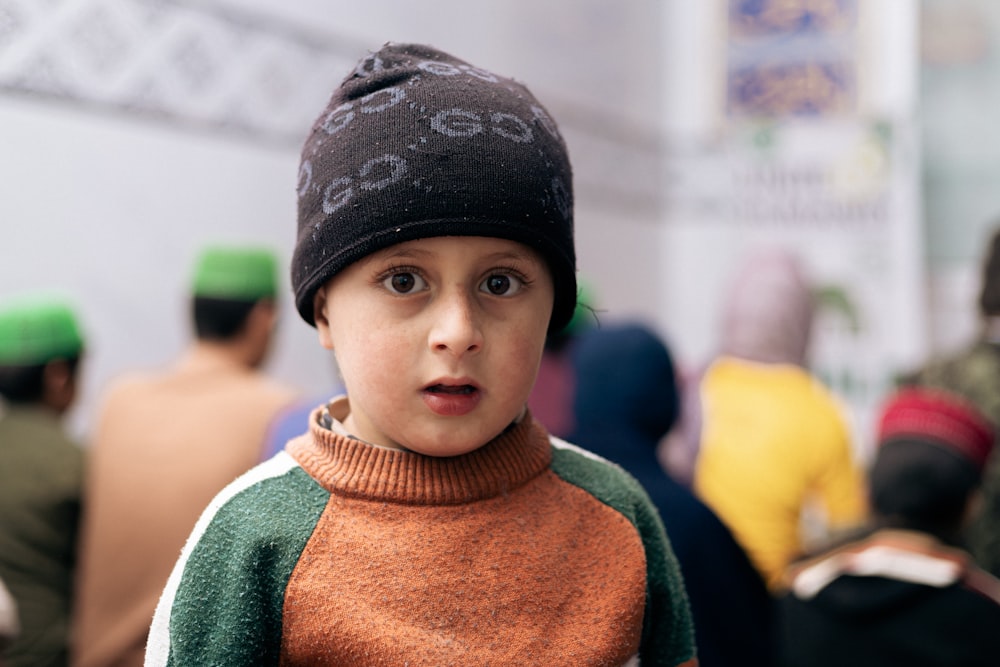 a young boy wearing a hat and a sweater