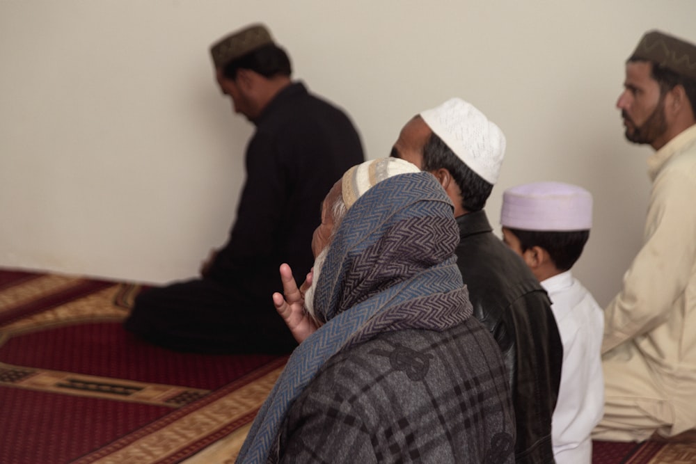 a group of men sitting on top of a rug