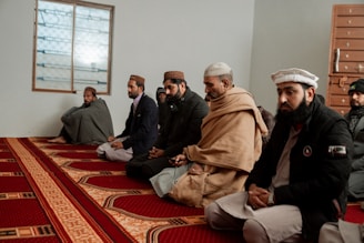 a group of men sitting on top of a red rug