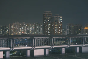 Nighttime image of a newly completed residential tower with illuminated glass facades reflecting urban energy.