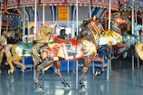 Colorful carousel with children riding horses, surrounded by vibrant park decorations and lights.