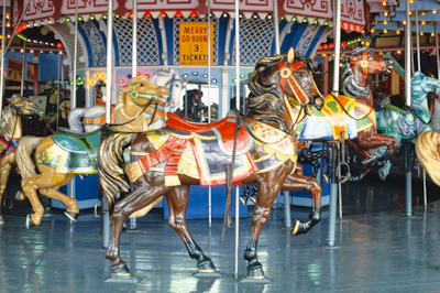 Colorful carousel with children riding horses, surrounded by vibrant park decorations and lights.