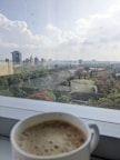 Guest enjoying a morning coffee on a balcony with a view of the bustling city below.