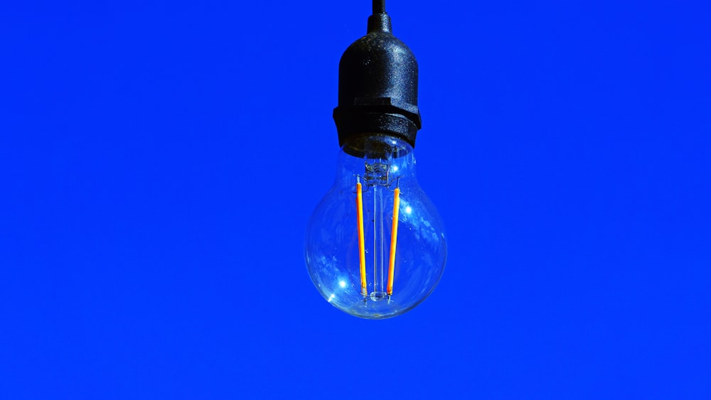 a light bulb hanging from a wire against a blue sky