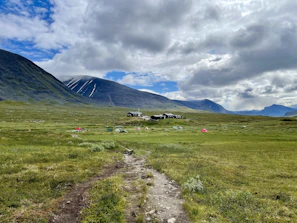 Colorful festival tents nestled in a lush green meadow with mountains in the background.