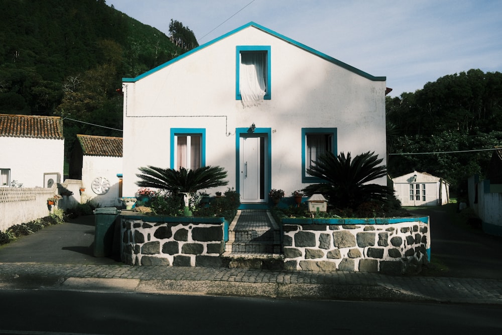 a white house with blue trim on a hill side