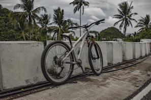 A rugged mountain bike resting against volcanic rocks under a cloudy Tenerife sky