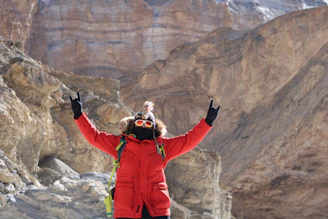a woman standing on top of a mountain with her arms in the air