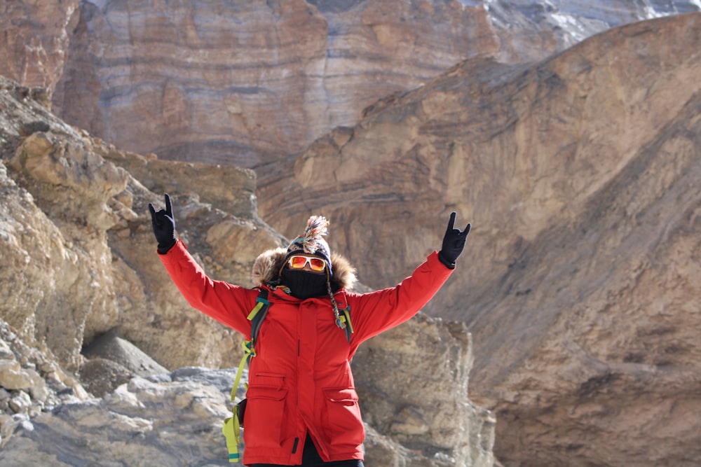 a woman standing on top of a mountain with her arms in the air