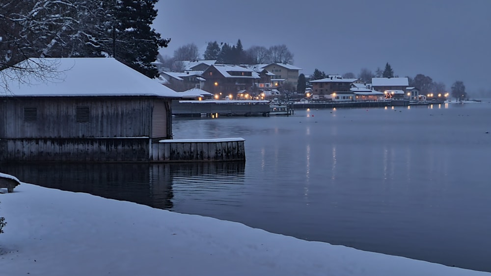 a body of water surrounded by snow covered trees