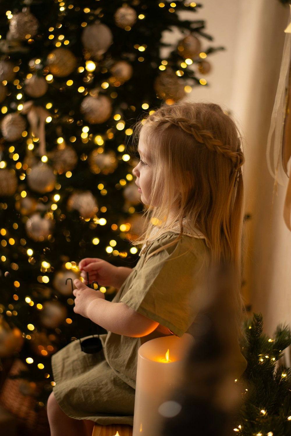 a little girl sitting in front of a christmas tree