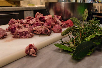 Close-up of fresh raw beef cuts arranged on a wooden board with herbs